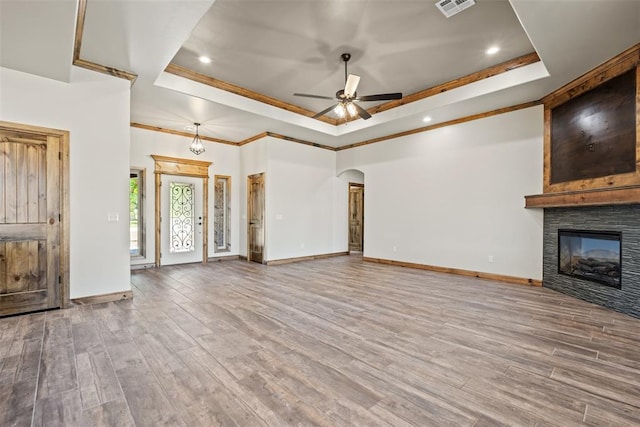 2414 Black Jack Way, Blanchard, OK 73010 - unfurnished living room featuring a tray ceiling, a ceiling fan, crown molding, arched walkways, and wood finished floors