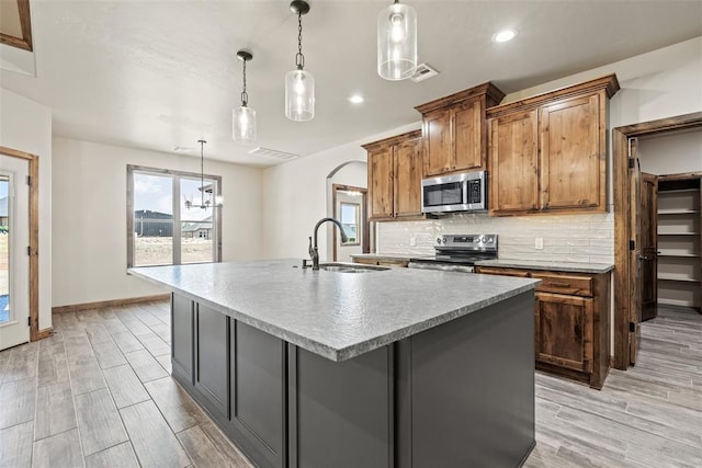 2414 Black Jack Way, Blanchard, OK 73010 - kitchen featuring stainless steel appliances, a sink, a center island with sink, decorative backsplash, and plenty of natural light