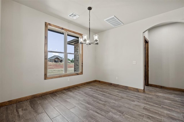 2414 Black Jack Way, Blanchard, OK 73010 - spare room featuring wood finished floors, a chandelier, arched walkways, and baseboards