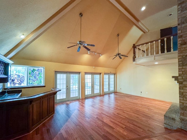 2010 Saddleback Blvd, Norman, OK 73072 - unfurnished living room with high vaulted ceiling, beam ceiling, wood finished floors, healthy amount of natural light, and ceiling fan