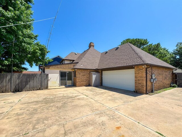 2010 Saddleback Blvd, Norman, OK 73072 - view of front of property featuring brick siding, driveway, an attached garage, a chimney, and roof with shingles