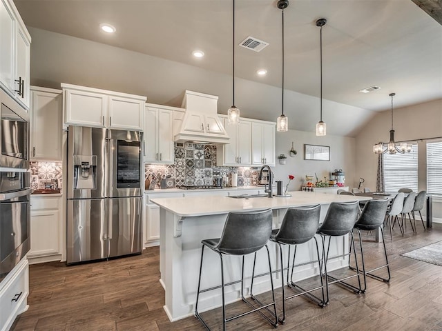 16112 Buffalo Dr, Oklahoma City, OK 73170 - kitchen with stainless steel appliances, custom exhaust hood, dark wood-type flooring, white cabinetry, and vaulted ceiling