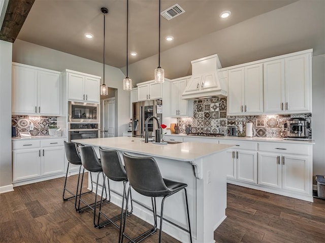 16112 Buffalo Dr, Oklahoma City, OK 73170 - kitchen with appliances with stainless steel finishes, premium range hood, decorative backsplash, a center island with sink, and dark wood-type flooring