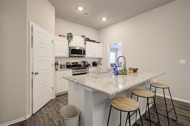 1301 Harvest Trl, Yukon, OK 73099 - kitchen featuring appliances with stainless steel finishes, a breakfast bar, dark wood-type flooring, white cabinets, and recessed lighting