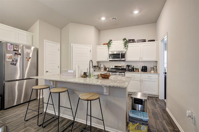 1301 Harvest Trl, Yukon, OK 73099 - kitchen with stainless steel appliances, wood finish floors, white cabinetry, a breakfast bar, and recessed lighting