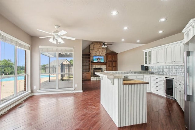 1329 S Southersby Dr, Mustang, OK 73064 - kitchen featuring a ceiling fan, wine cooler, open floor plan, a stone fireplace, and vaulted ceiling