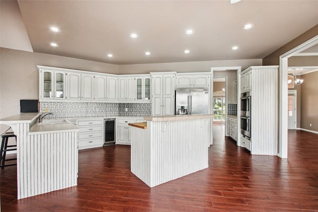 1329 S Southersby Dr, Mustang, OK 73064 - kitchen featuring wine cooler, appliances with stainless steel finishes, a breakfast bar, glass insert cabinets, and recessed lighting