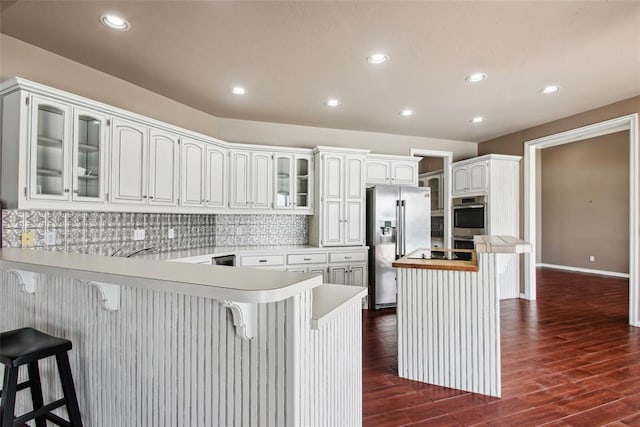 1329 S Southersby Dr, Mustang, OK 73064 - kitchen featuring stainless steel appliances, a peninsula, glass insert cabinets, a kitchen breakfast bar, and recessed lighting