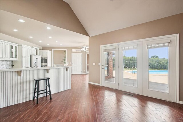 1329 S Southersby Dr, Mustang, OK 73064 - kitchen with stainless steel refrigerator with ice dispenser, a kitchen breakfast bar, a peninsula, dark wood-style floors, and white cabinetry
