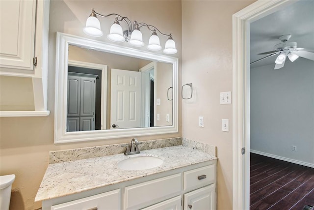 1329 S Southersby Dr, Mustang, OK 73064 - half bathroom featuring vanity, toilet, wood finished floors, ceiling fan, and baseboards