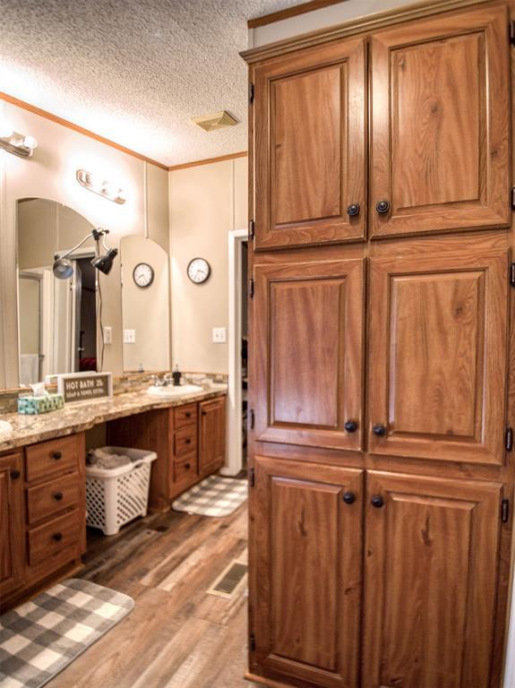15026 N County Road 3370th Rd, Stratford, OK 74872 - bathroom featuring wood finished floors, vanity, a textured ceiling, and crown molding