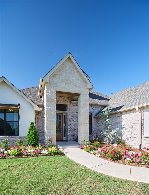 9117 SW 90th St, Mustang, OK 73064 - view of front of property featuring a shingled roof, a front lawn, brick siding, and stone siding