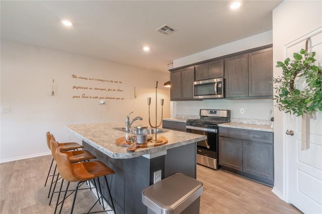 3429 Molly Dr, Yukon, OK 73099 - kitchen with stainless steel appliances, a sink, light wood-style floors, a kitchen bar, and recessed lighting
