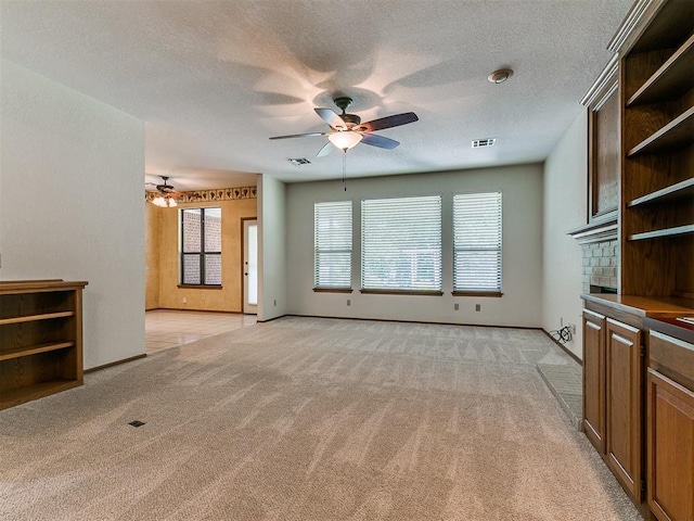 2601 Northwood Ln, Edmond, OK 73013 - unfurnished living room featuring ceiling fan, light colored carpet, healthy amount of natural light, a textured ceiling, and baseboards