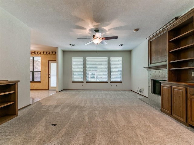 2601 Northwood Ln, Edmond, OK 73013 - unfurnished living room with a ceiling fan, light carpet, a brick fireplace, baseboards, and a textured ceiling