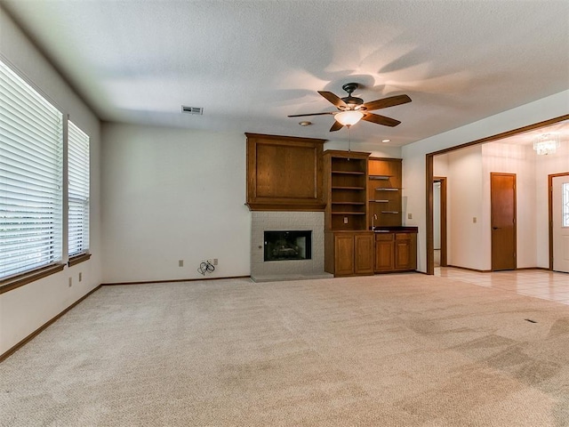 2601 Northwood Ln, Edmond, OK 73013 - unfurnished living room with ceiling fan, light carpet, a fireplace with flush hearth, baseboards, and a sink