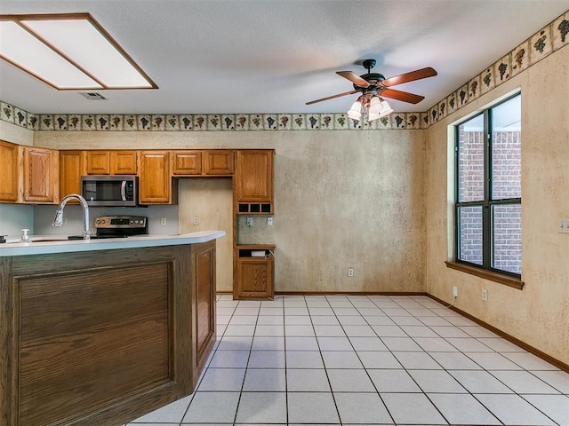 2601 Northwood Ln, Edmond, OK 73013 - kitchen featuring appliances with stainless steel finishes, light countertops, brown cabinets, and a sink