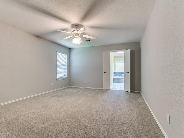 2601 Northwood Ln, Edmond, OK 73013 - empty room with light colored carpet, ceiling fan, a textured ceiling, and baseboards