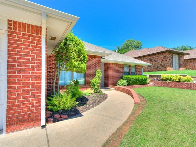 2601 Northwood Ln, Edmond, OK 73013 - doorway to property with brick siding, a lawn, and roof with shingles