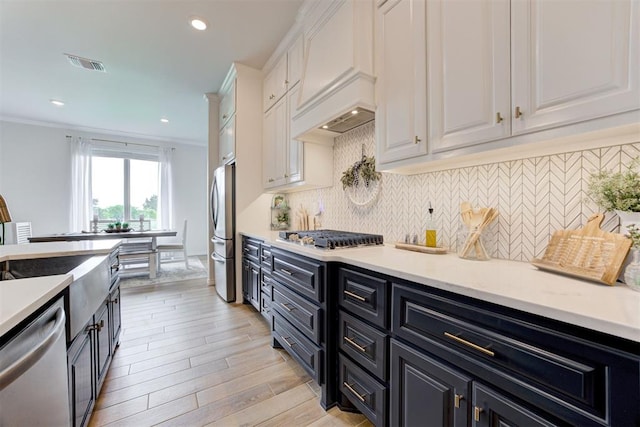 5804 NW 159th St, Edmond, OK 73013 - kitchen featuring appliances with stainless steel finishes, white cabinetry, premium range hood, decorative backsplash, and ornamental molding