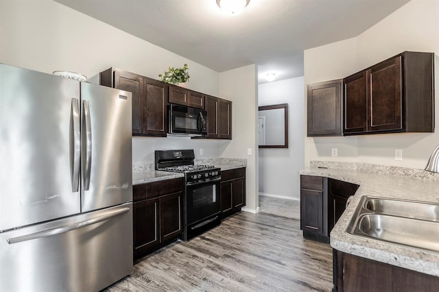 5318 Kye Dr, Tuttle, OK 73089 - kitchen with black appliances, a sink, dark brown cabinetry, light wood-style floors, and baseboards