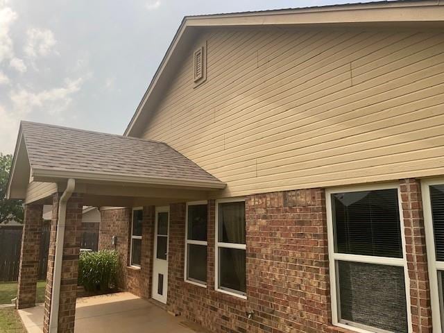 9520 SW 24th Ter, Oklahoma City, OK 73128 - view of property exterior featuring brick siding, a patio, and a shingled roof