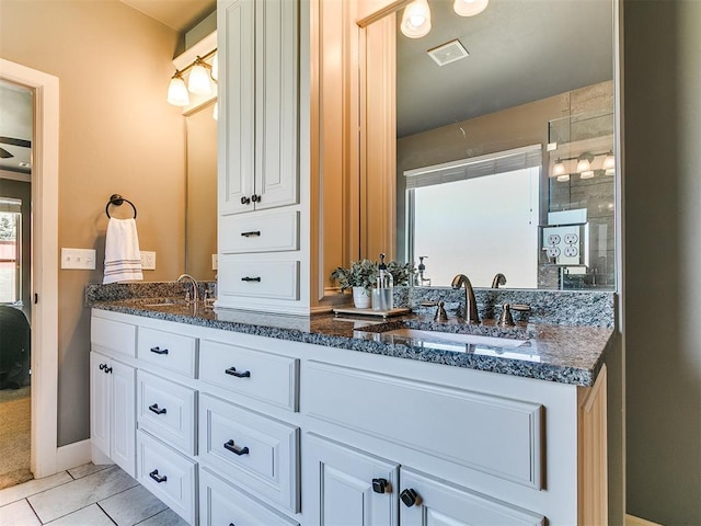 14210 Jack Rabbit Trl, Arcadia, OK 73007 - bathroom featuring double vanity, tile patterned floors, a tile shower, and baseboards