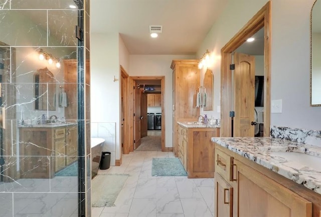 9027 Ns 3500th Rd, Prague, OK 74864 - bathroom featuring two vanities, a freestanding bath, marble look tile flooring, and washer / dryer