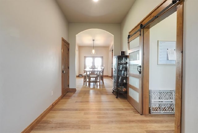 9027 Ns 3500th Rd, Prague, OK 74864 - hall featuring light wood-type flooring, arched walkways, a barn door, and baseboards