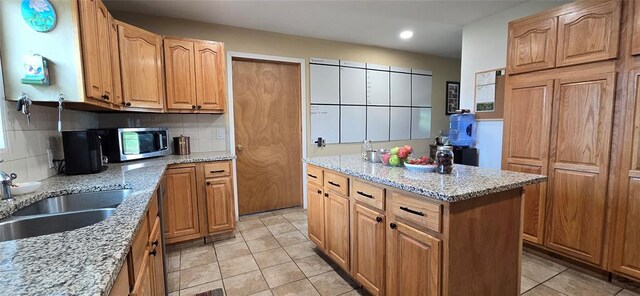 36797 N 56th Hwy, Okemah, OK 74859 - kitchen with a center island, light tile patterned floors, stainless steel microwave, light stone countertops, and backsplash