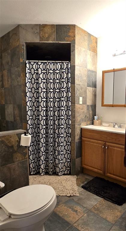 36797 N 56th Hwy, Okemah, OK 74859 - bathroom with tile walls, stone tile floors, vanity, a shower with curtain, and toilet