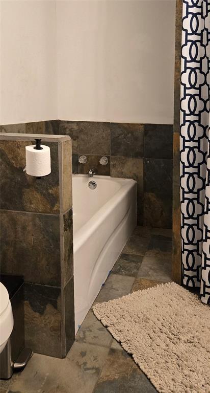 36797 N 56th Hwy, Okemah, OK 74859 - full bath with a wainscoted wall, a garden tub, stone finish flooring, tile walls, and toilet