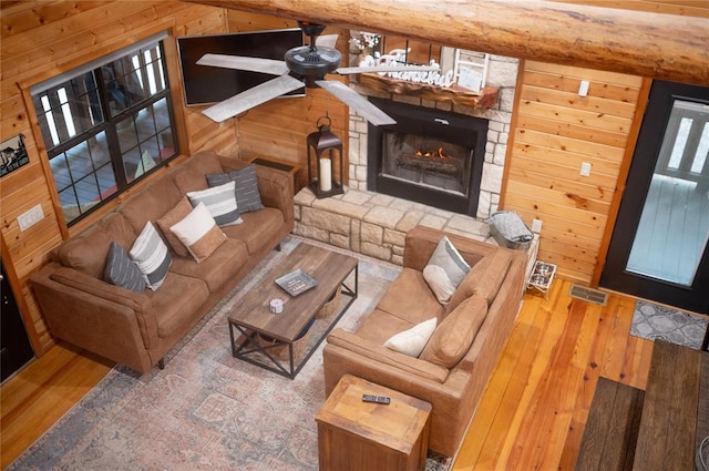 173 Alexis Ln, Broken Bow, OK 74728 - living area featuring wooden walls, hardwood / wood-style flooring, a stone fireplace, a ceiling fan, and vaulted ceiling