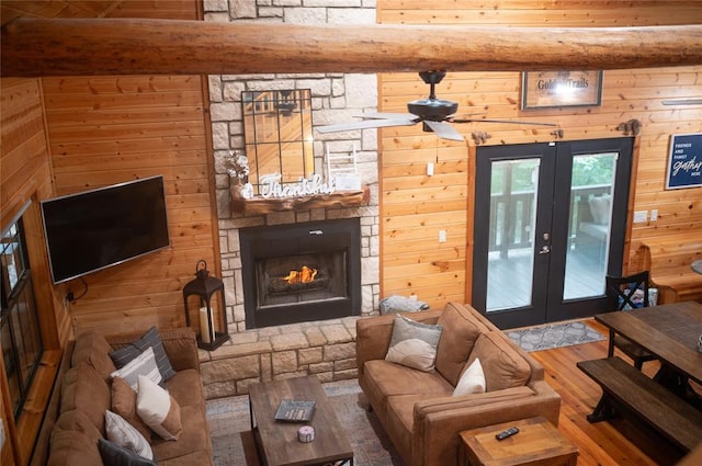 173 Alexis Ln, Broken Bow, OK 74728 - living area featuring french doors, hardwood / wood-style floors, wooden walls, a stone fireplace, and beamed ceiling