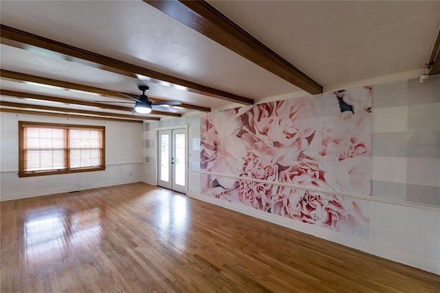 1301 W C Ave, Elk City, OK 73644 - empty room featuring french doors, wood finished floors, beam ceiling, a ceiling fan, and a decorative wall