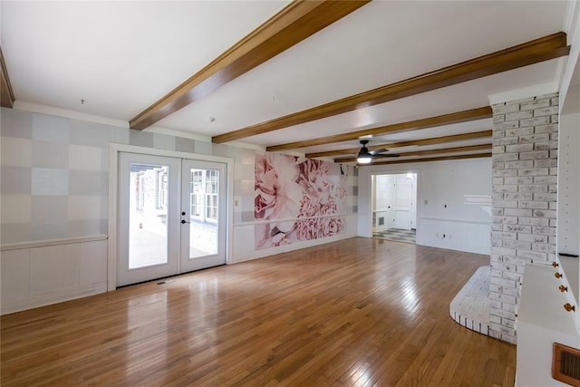 1301 W C Ave, Elk City, OK 73644 - unfurnished living room featuring wood finished floors, french doors, beam ceiling, a ceiling fan, and a decorative wall