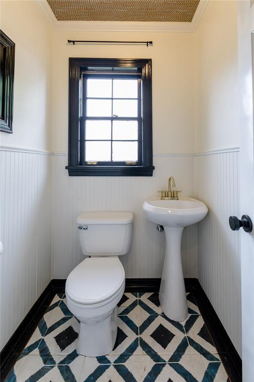 1301 W C Ave, Elk City, OK 73644 - bathroom with toilet, ornamental molding, a wainscoted wall, and tile patterned flooring