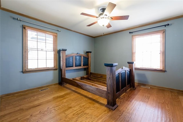 1301 W C Ave, Elk City, OK 73644 - bedroom with wood finished floors, crown molding, baseboards, multiple windows, and ceiling fan