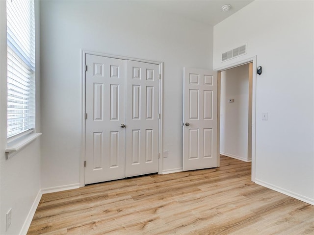 16020 Panther Way, Edmond, OK 73013 - unfurnished bedroom featuring light wood-style floors, a closet, baseboards, and a towering ceiling