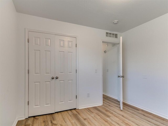 16020 Panther Way, Edmond, OK 73013 - unfurnished bedroom with light wood-type flooring, baseboards, and a closet