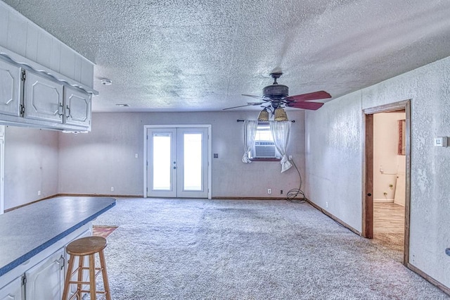 1110 Lollar Dr, Maysville, OK 73057 - unfurnished living room with light carpet, ceiling fan, a textured ceiling, french doors, and baseboards