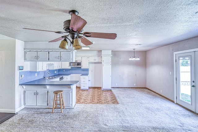 1110 Lollar Dr, Maysville, OK 73057 - kitchen with stainless steel microwave, a sink, a peninsula, a chandelier, and light colored carpet