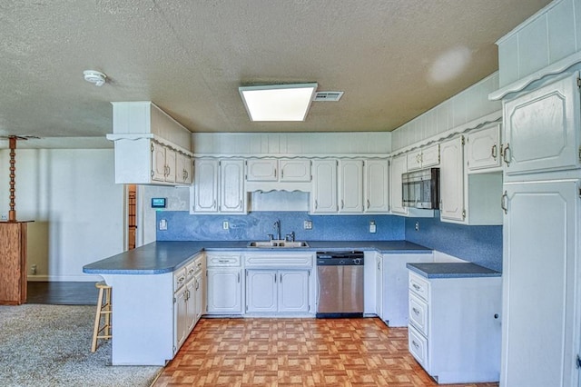 1110 Lollar Dr, Maysville, OK 73057 - kitchen featuring appliances with stainless steel finishes, a peninsula, a sink, a textured ceiling, and dark countertops