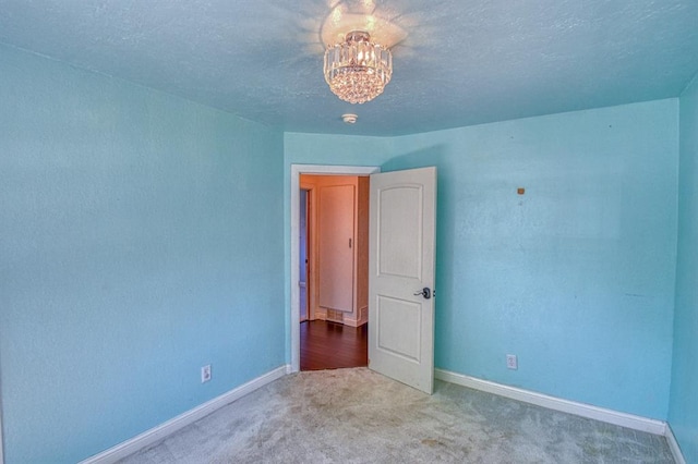 1110 Lollar Dr, Maysville, OK 73057 - carpeted empty room featuring baseboards, a chandelier, and a textured ceiling