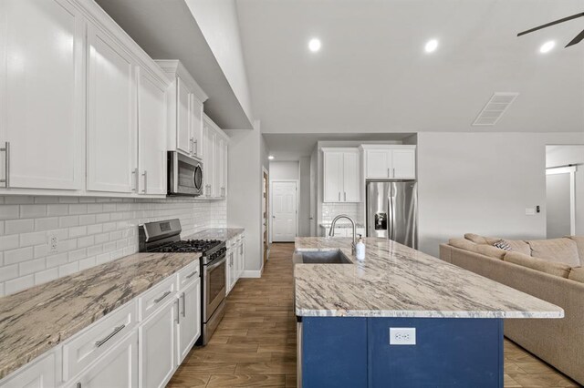 2382 County Road 1262, Blanchard, OK 73010 - kitchen with stainless steel appliances, a sink, open floor plan, white cabinetry, and a kitchen island with sink