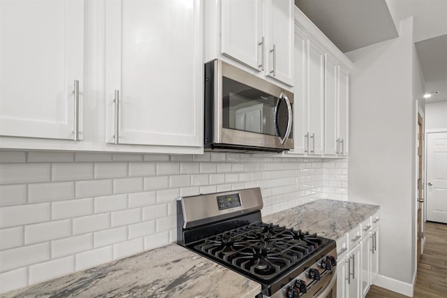 2382 County Road 1262, Blanchard, OK 73010 - kitchen with appliances with stainless steel finishes, white cabinets, light stone countertops, wood finished floors, and decorative backsplash