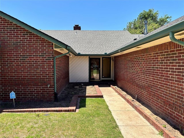 3113 Shannon Ct, Bethany, OK 73008 - doorway to property with a chimney, brick siding, a lawn, and roof with shingles