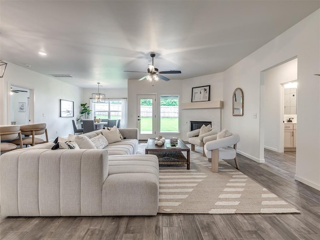 2257 Preserve Edge Dr, Edmond, OK 73034 - living area featuring a ceiling fan, a glass covered fireplace, wood finished floors, baseboards, and a chandelier