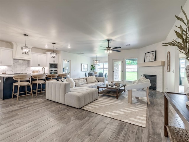 2257 Preserve Edge Dr, Edmond, OK 73034 - living area featuring light wood-style flooring, ceiling fan, a fireplace, and a chandelier