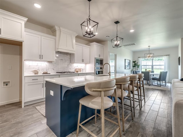 2257 Preserve Edge Dr, Edmond, OK 73034 - kitchen with a chandelier, premium range hood, appliances with stainless steel finishes, white cabinetry, and recessed lighting